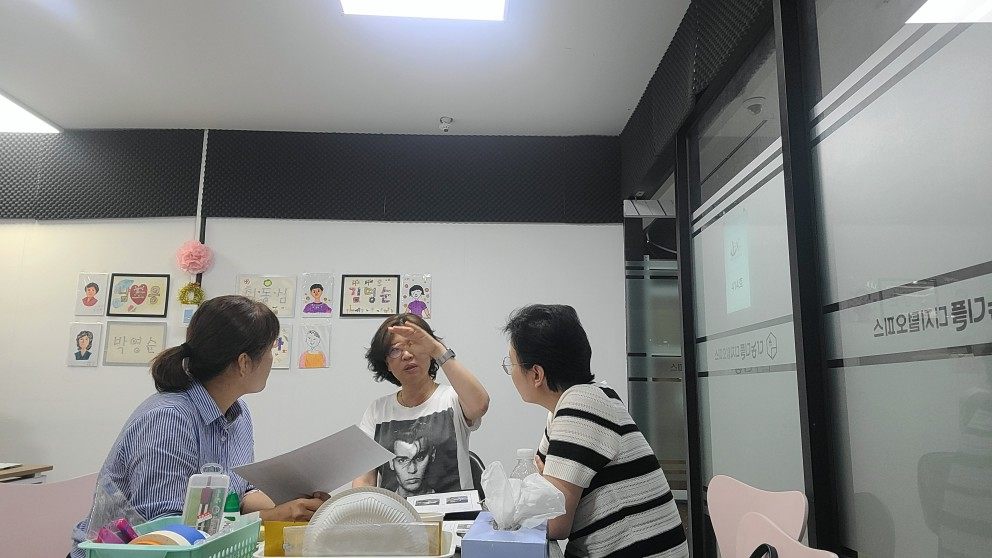단체 사무실에서 세 사람이 마주 서서 상담하고 있다